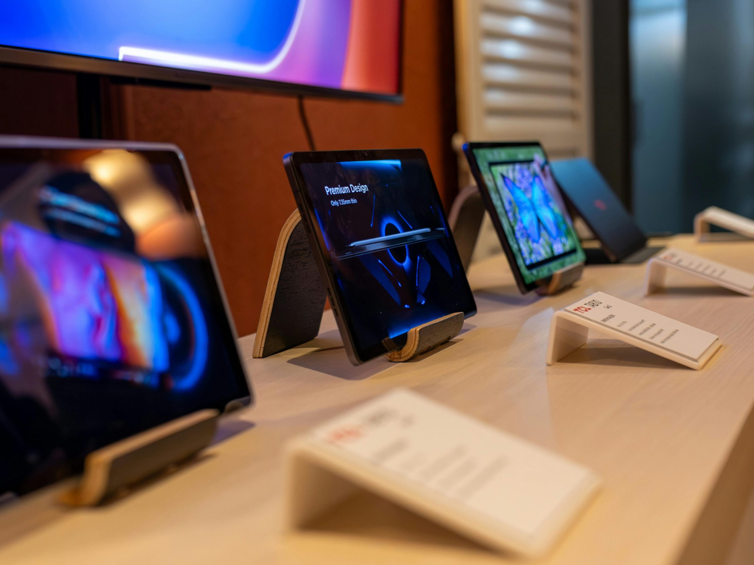 A selection of tablets showcased on a table in a tech retail store.