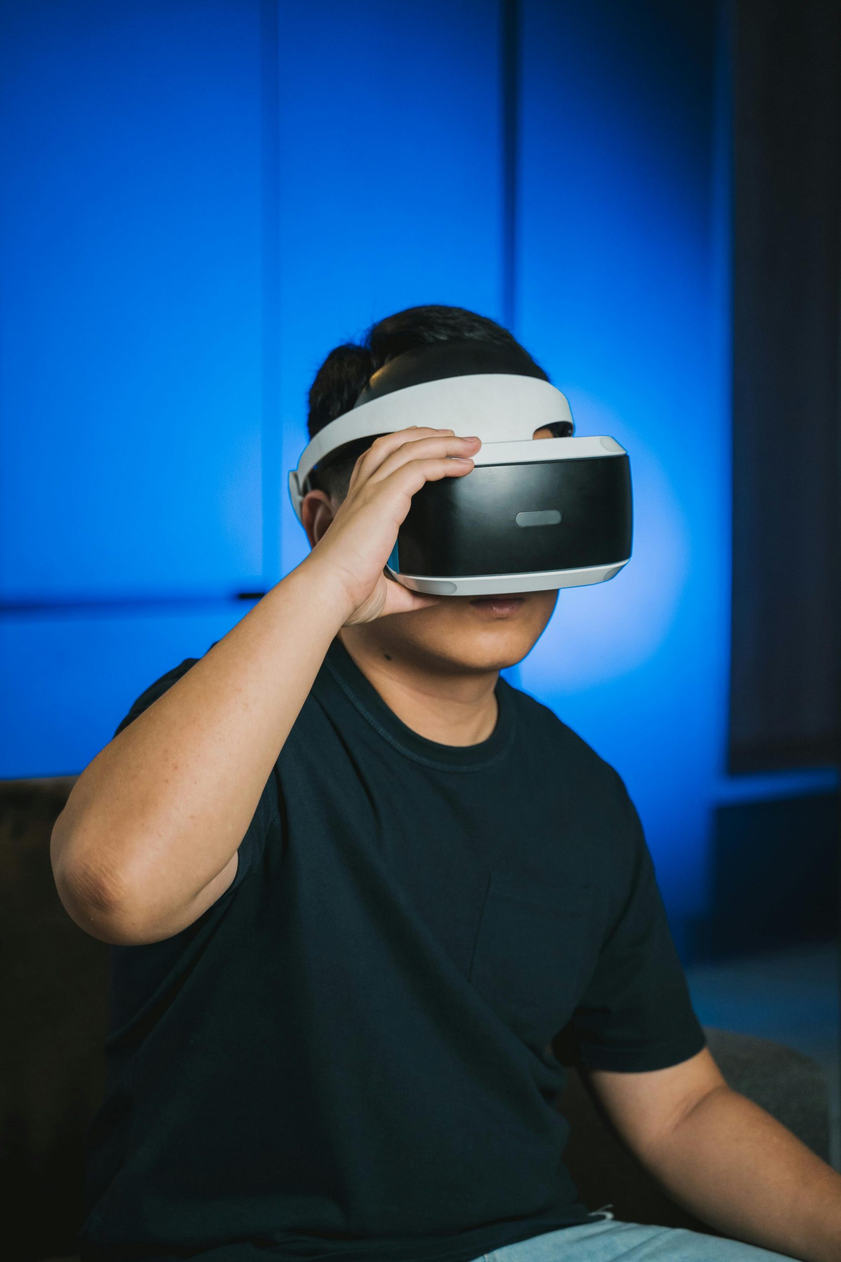 A man immersed in a virtual reality experience indoors with futuristic VR glasses and ambient lighting.